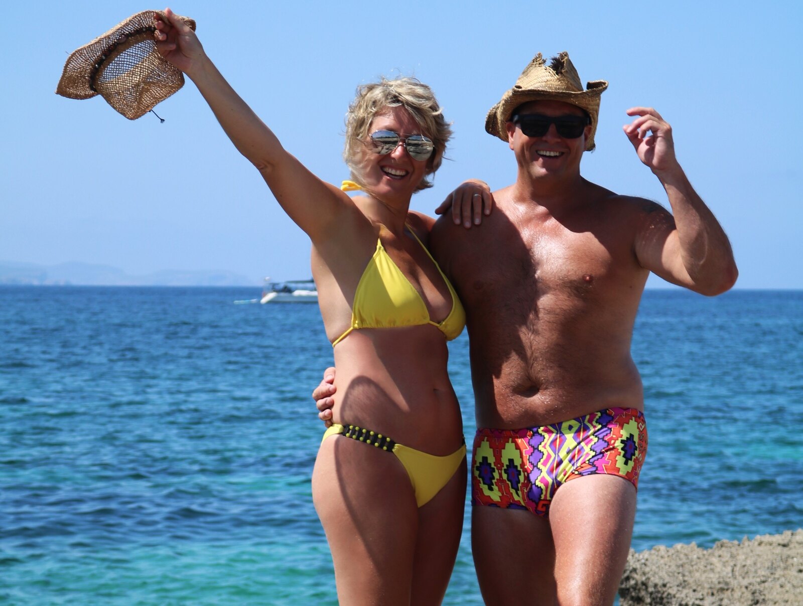 Woman wearing the yellow FISHKISS Amarillo bikini beside a man in matching swimwear