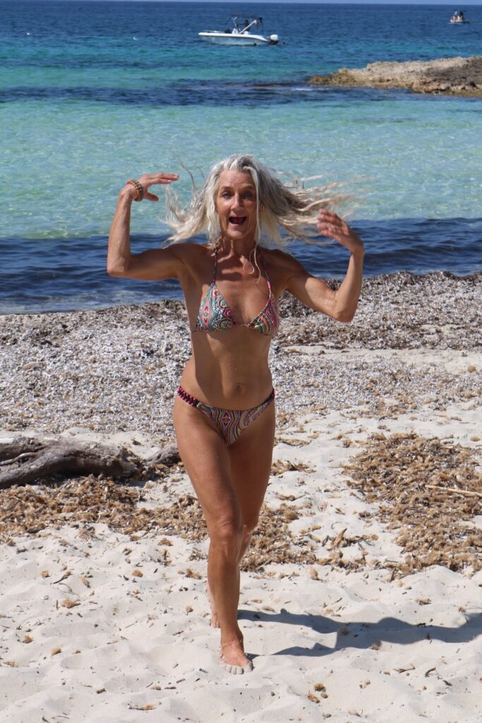 Lachende Frau in einem farbenfrohen Paisley-Bikini am Meer auf Mallorca.